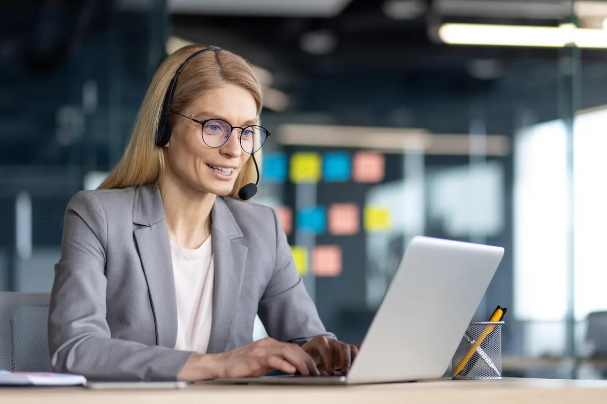 Frau mit Headset am Laptop – Telefonansage im KI-Tonstudio erstellen